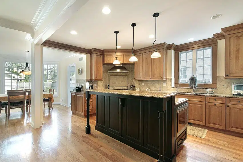 Kitchen with island, countertops, backsplash, pecan wood cabinets, windows, and pendant lighting fixtures