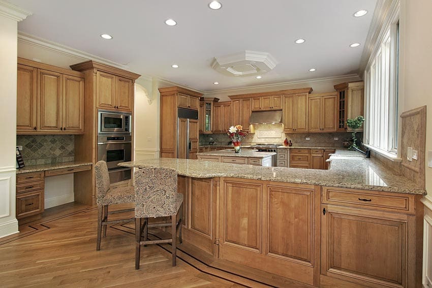Kitchen with pecan cabinets, countertop, wood flooring, backsplash, windows, and ceiling lights