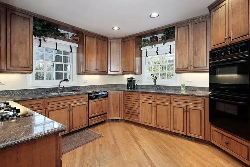 Kitchen with pecan cabinets, wood floors, countertop, windows, and oven
