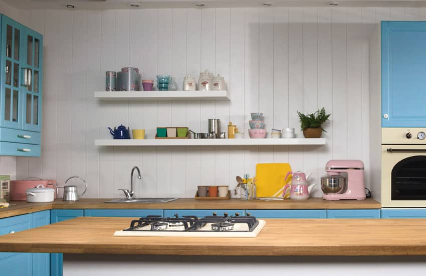 Kitchen with floating shelves, blue cabinets and wood countertops