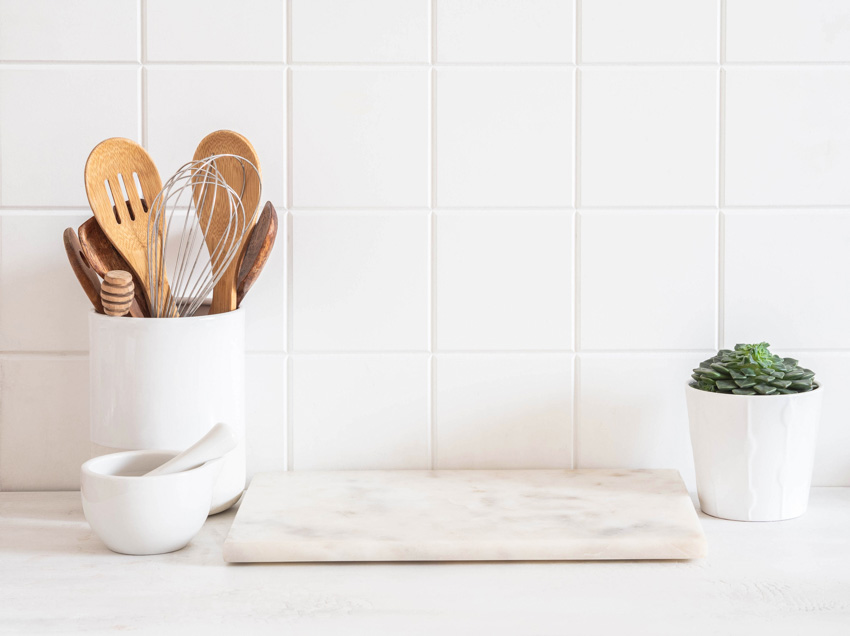 Kitchen with tile backsplash, wood utensils, and marble cutting board