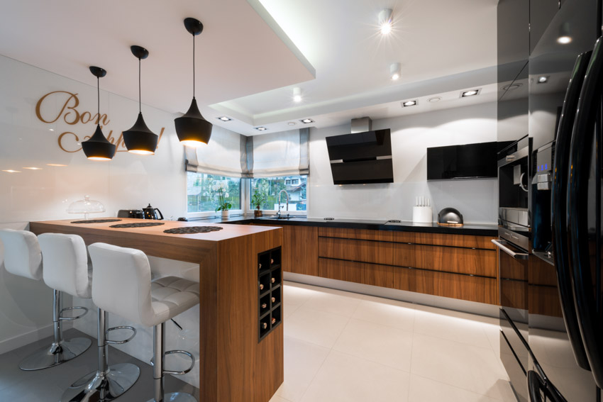 Kitchen with wood cabinets, wine storage, bar, hanging light, tufted bar stools, and countertop