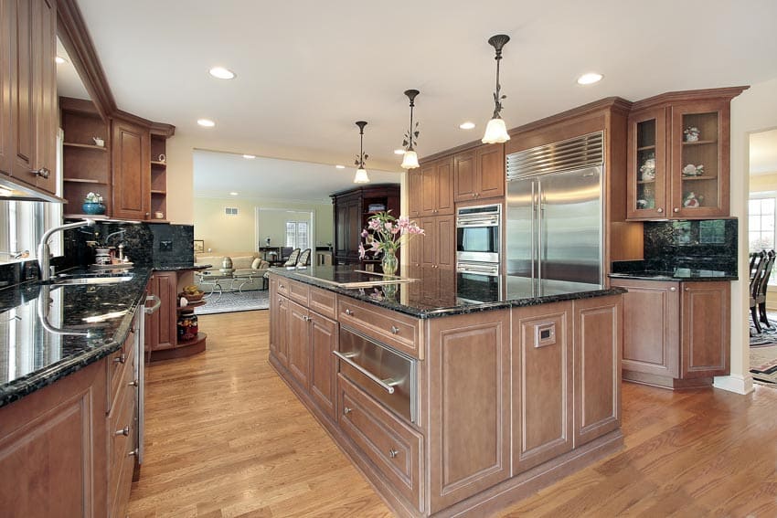 Kitchen with wood flooring, center island, countertops, pendant lights, and pecan cabinets