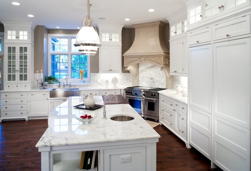 A large kitchen with pendant lights, island and white shaker cabinets