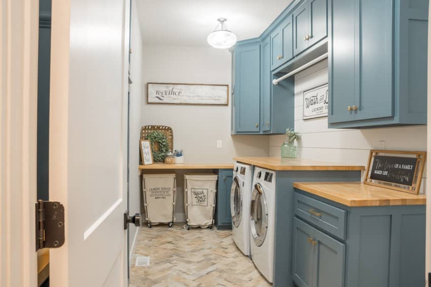Laundry room with Herringbone patterned tile floor, cabinets, countertop, dryer, and washing machine