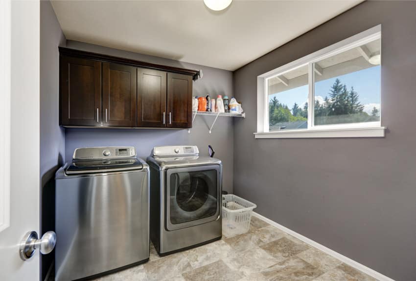 Laundry room with tile floors, washing machine, dryer, wood cabinets, and windows