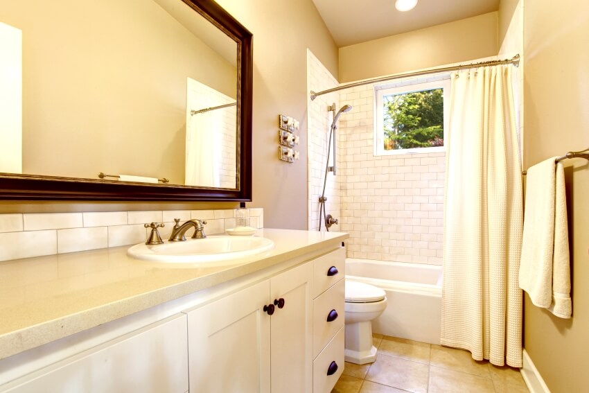 Light bathroom interior with white cabinet, and brick tile wall in shower with curved curtain rod
