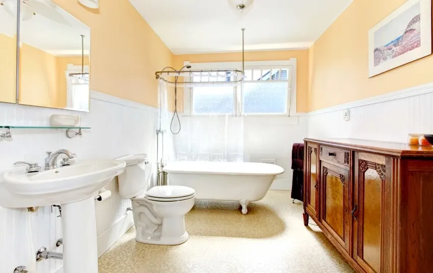 Light tones bathroom with an antique cabinet and freestanding clawfoot bath tub