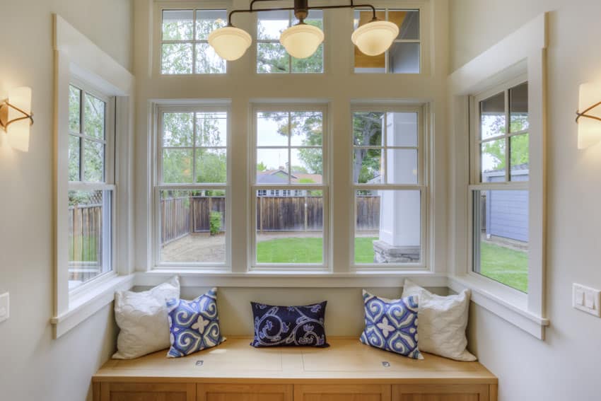 Living room nook area with triple pane windows, cushioned seating, and pillows