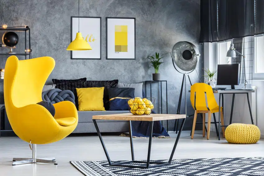 Room with accent table, yellow egg chair, concrete wall, couch, lamp, plants, home office area, and windows