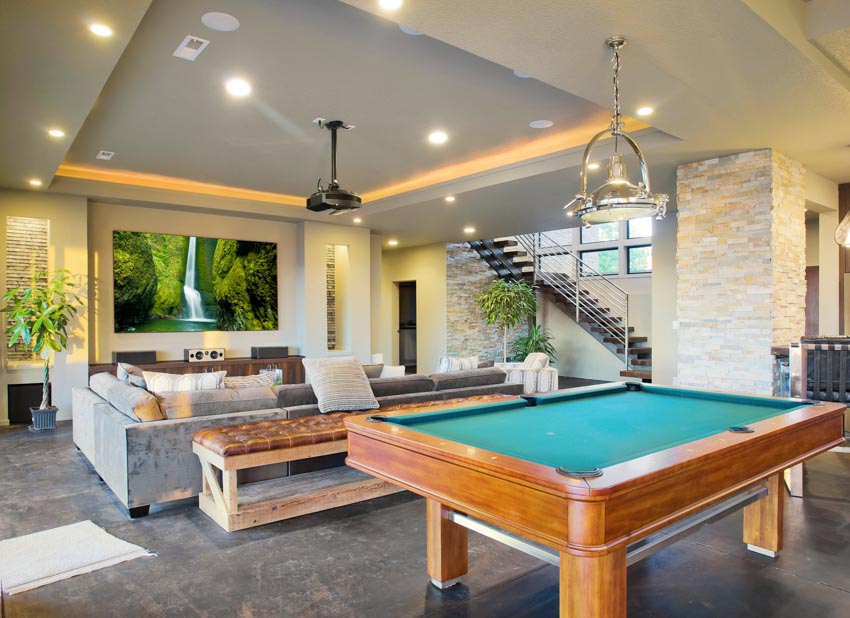Living room with couch, billiards table, hanging light, television, bench, and indoor plants