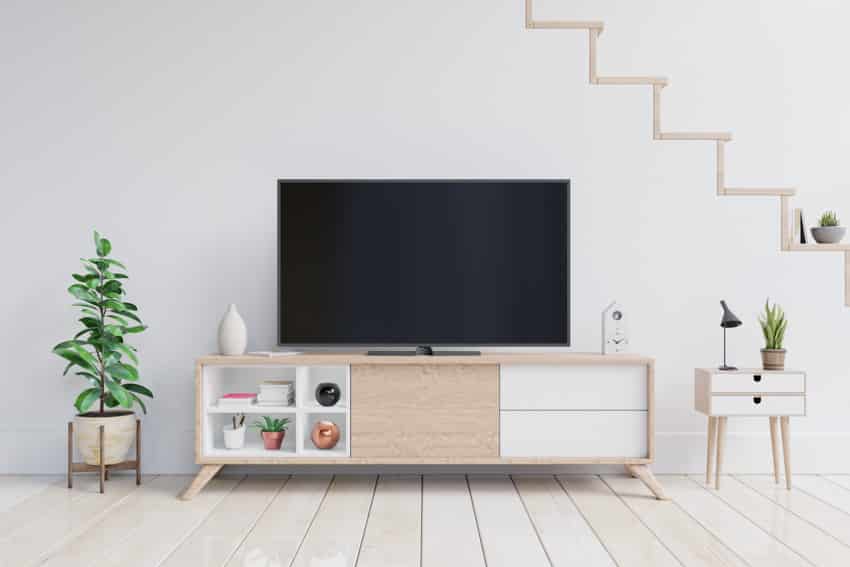 Room with media table, television, plants, and wooden flooring