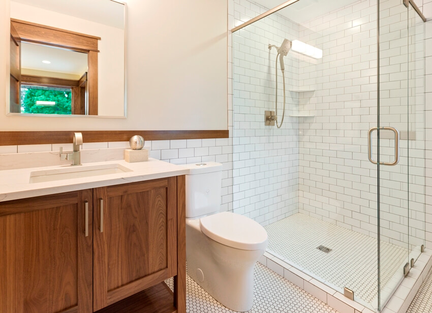 A lovely bathroom with subway wall tile, penny tile flooring and brown cabinets