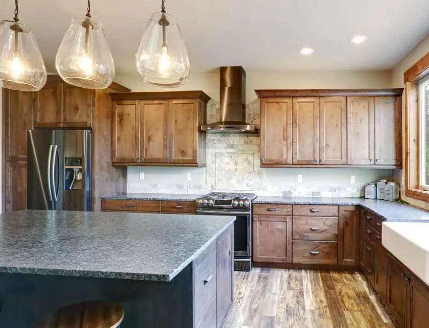 A luxurious open plan kitchen design with large center island, rustic alder cabinets, and stainless steel appliances