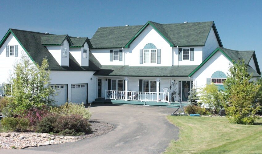 Luxury white house with big front lawn and green painted roof