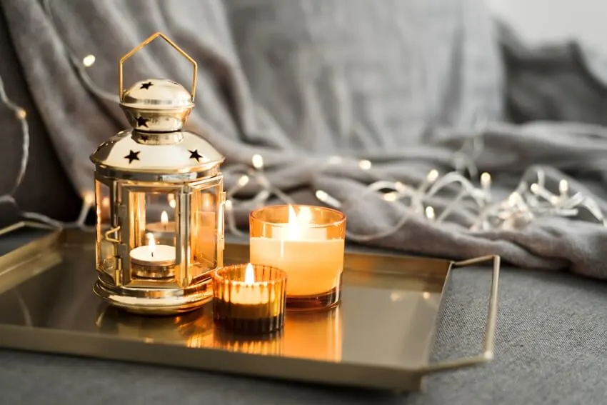 A metal lantern and burning candles on a golden metal tray