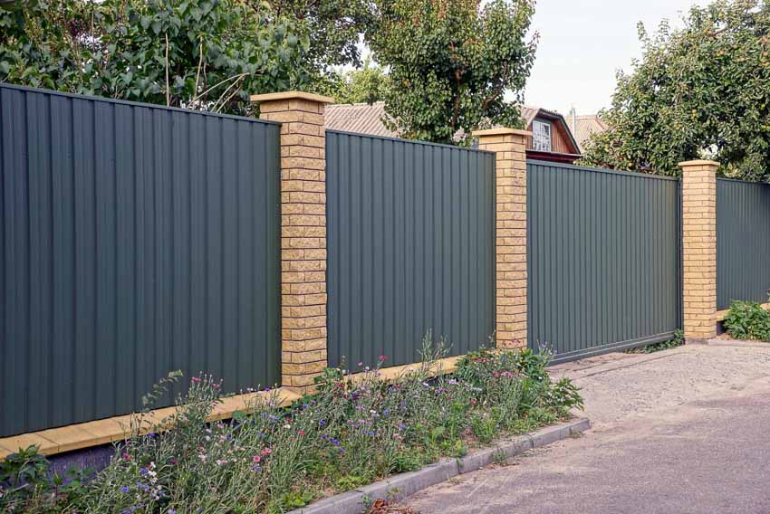 Metal privacy fence supported by brick pillars