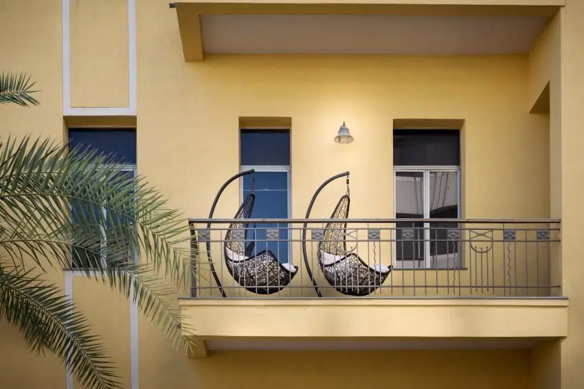 Modern balcony on a yellow building with two black swing chairs