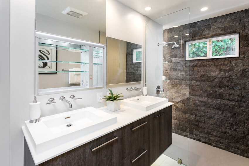 Modern bathroom with custom mirror and laminate countertop with two sinks near shower glass wall