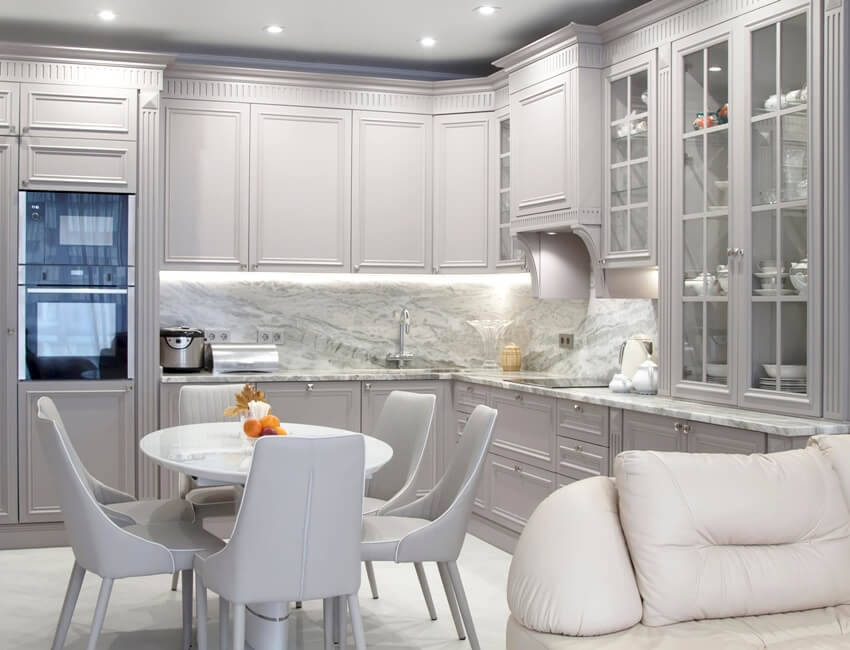 Kitchen with grey cabinets, under cabinet lighting and marble backsplash