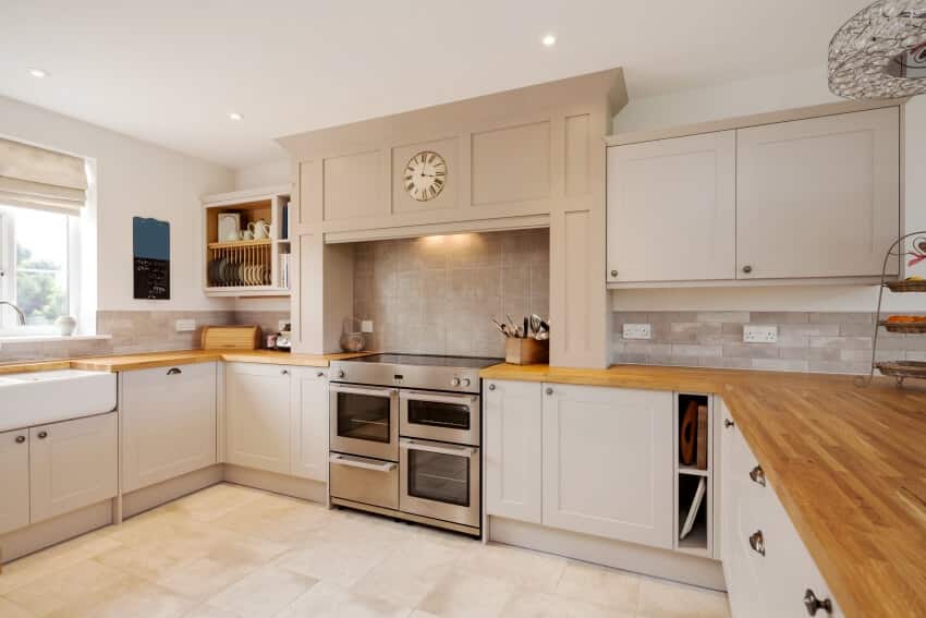 Modern kitchen interior with fitted appliances including wood tile countertops and worksurfaces, cupboards and drawers