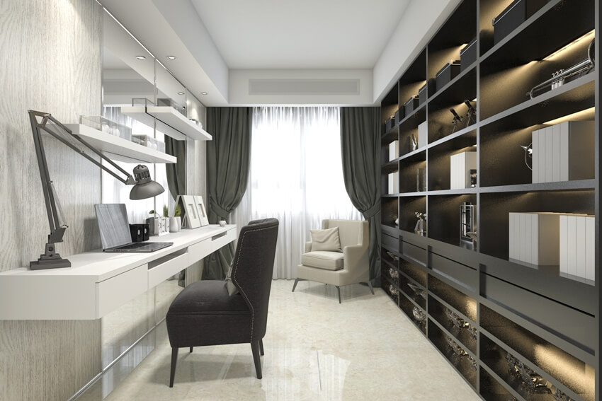 A modern luxury working room with side tab file cabinets, armchairs, and floating desk with laptop and lamp