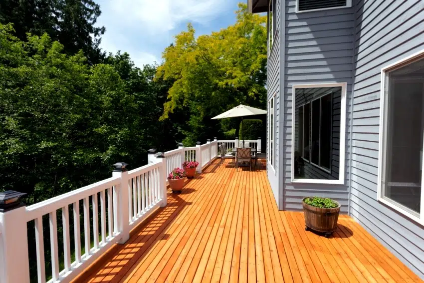 Newly stained outdoor wooden deck surrounded with trees on a sunny afternoon