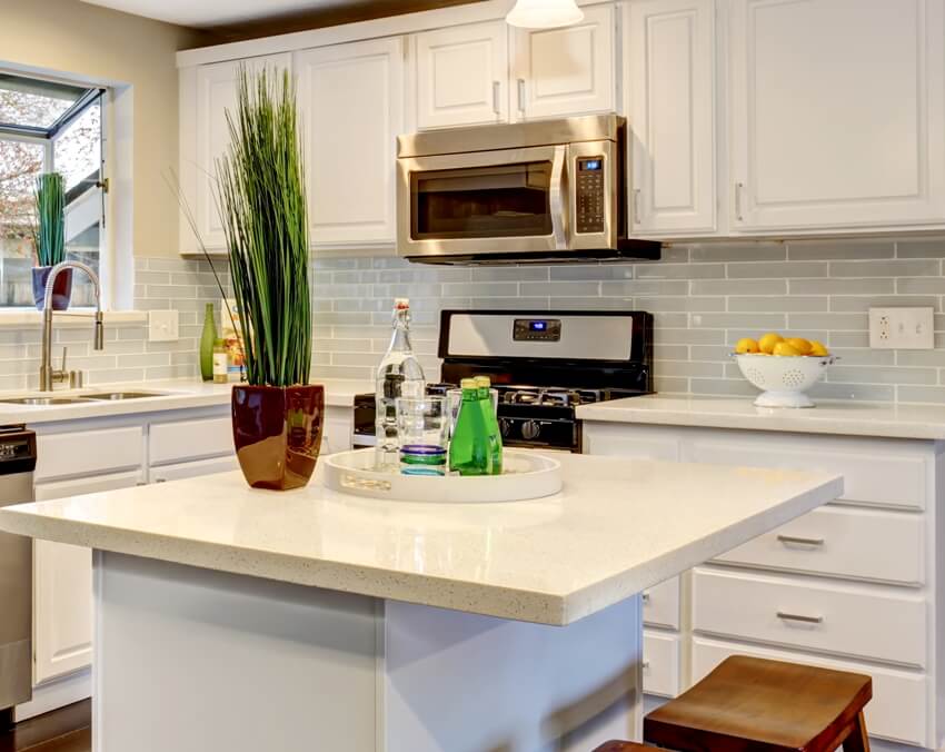 Nice kitchen in modern home including island, white counter tops and microwave with defrost preset timer