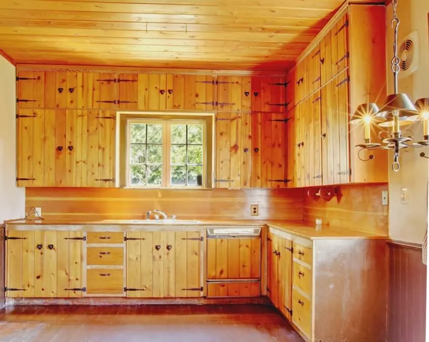 An old kitchen interior with wooden floors, knotty pine kitchen cabinets and ceiling
