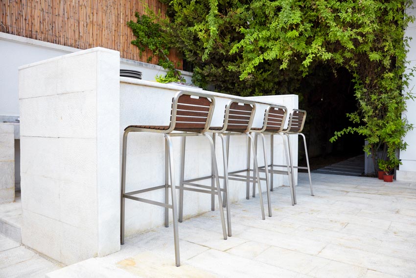Outdoor area with bar area, wood fence, foliage, and ladder bar stools