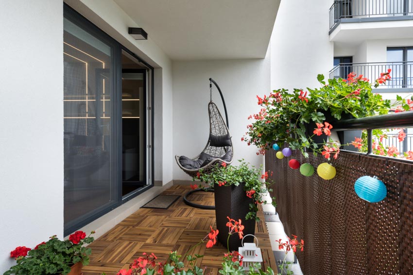 Outdoor area with glass sliding patio door, egg chair, wood floor, plants, and flowers