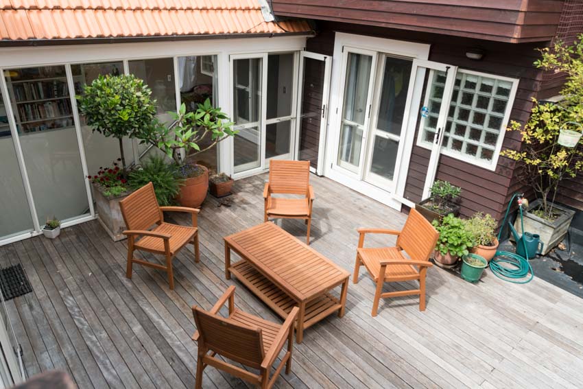 Outdoor area with patio door, table, chairs, plants, and wood floors