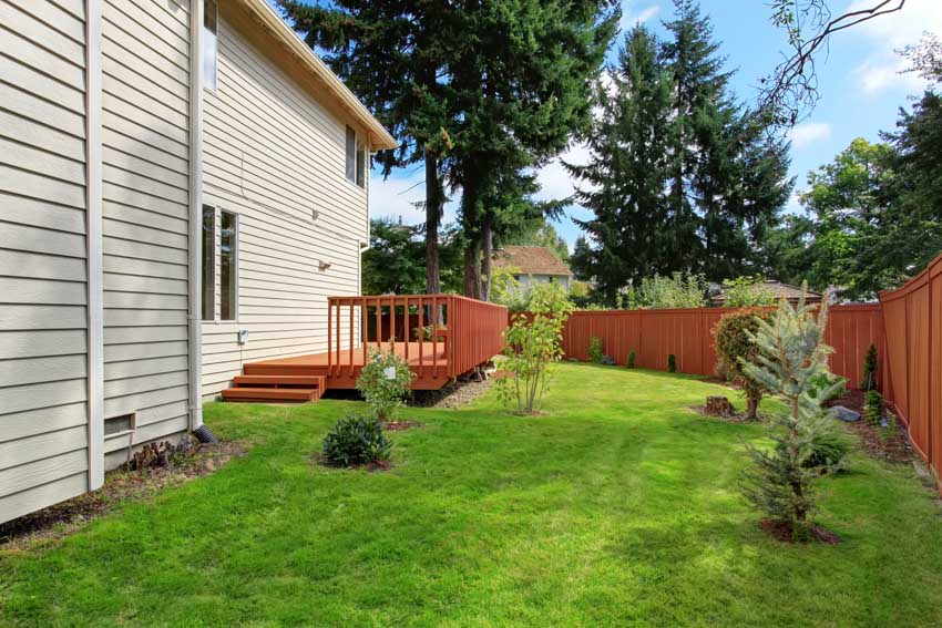 Outdoor area with redwood fencing, grassy area, and white wood siding