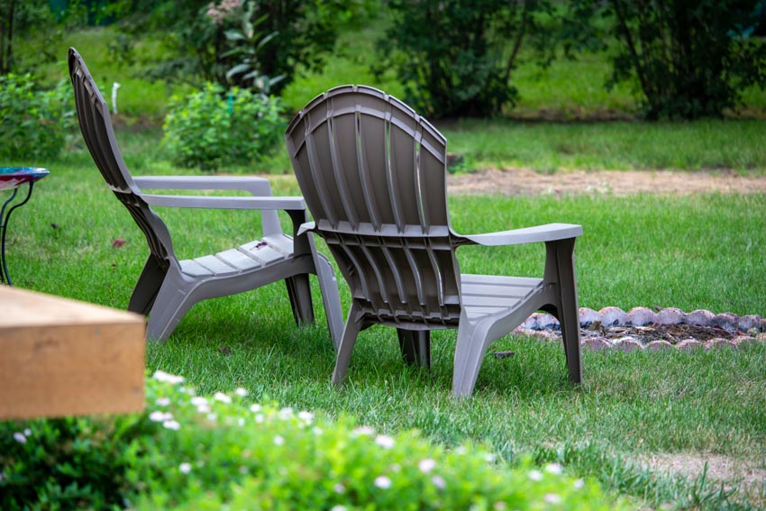 Outdoor area with two gray Muskoka chairs placed on a grassy field