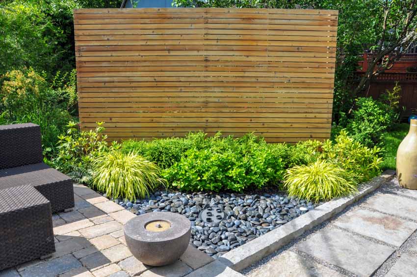 Outdoor area with wooden privacy wall, chairs, concrete walkway, and plants