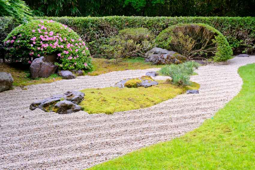 Outdoor garden with sand landscape features, hedge plants, and flowers