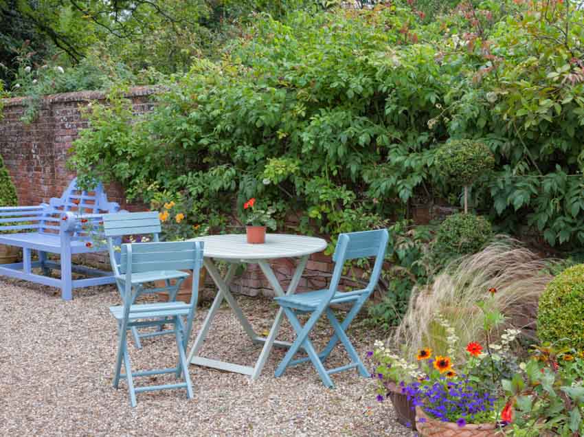 Outdoor gravel garden area with chairs, tables, plants, and flowers