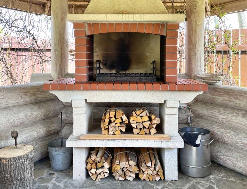 Outdoor kitchen with fireplace, pizza oven, and chopped firewood