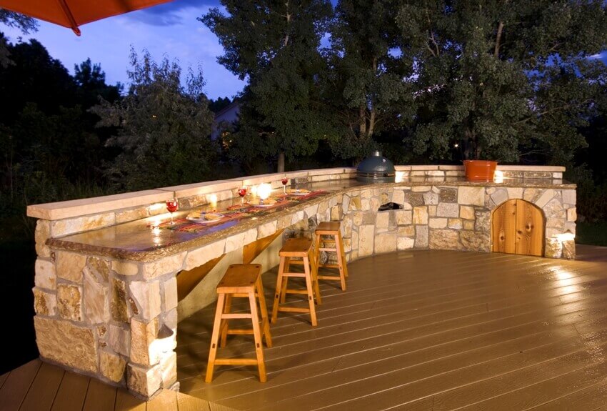 Outdoor kitchen with flagstone countertop on backyard at dusk