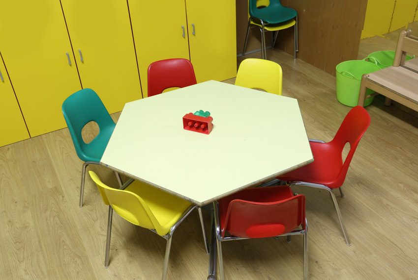 Playroom with polygon shaped table, colorful chairs, and yellow closets
