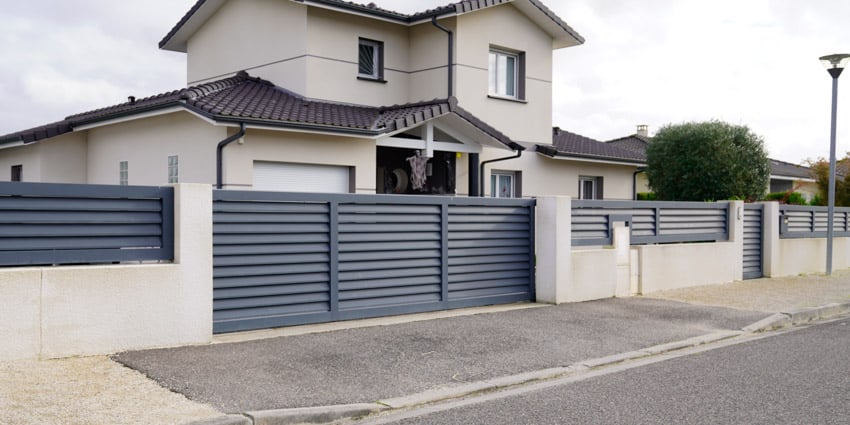 Residential property with horizontal slatted fences, gates, pitched roof, and windows