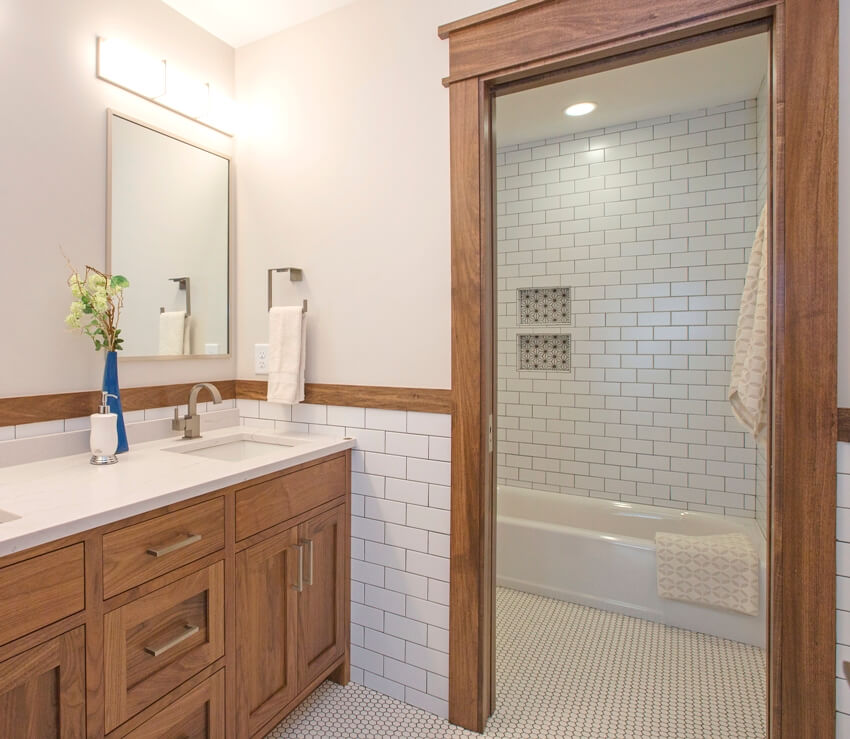 Shower and tub with penny tile floors and sink with wooden cabinets in separate section of bathroom
