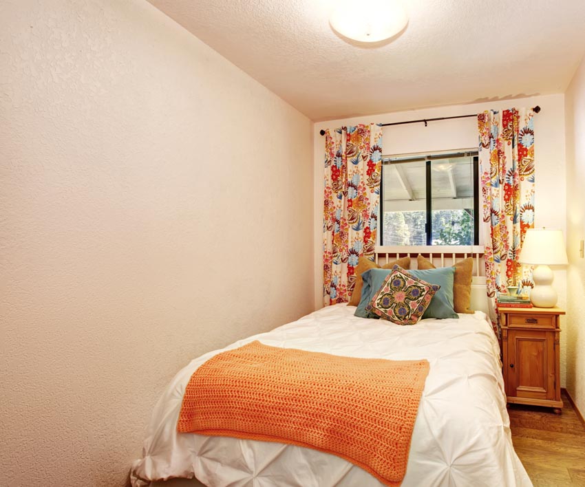 Simple bedroom with comforter, window, and narrow wood nightstand