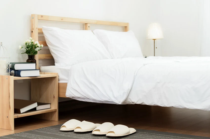Simple bed with white sheets, and square nightstand