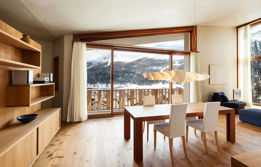 White seasonal curtains on a wide window overlooking a snowy mountain