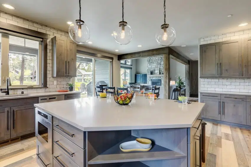 A stunning kitchen with grey tone interior light hardwood, stained knotty alder cabinets, and rustic modern island with colorful plates