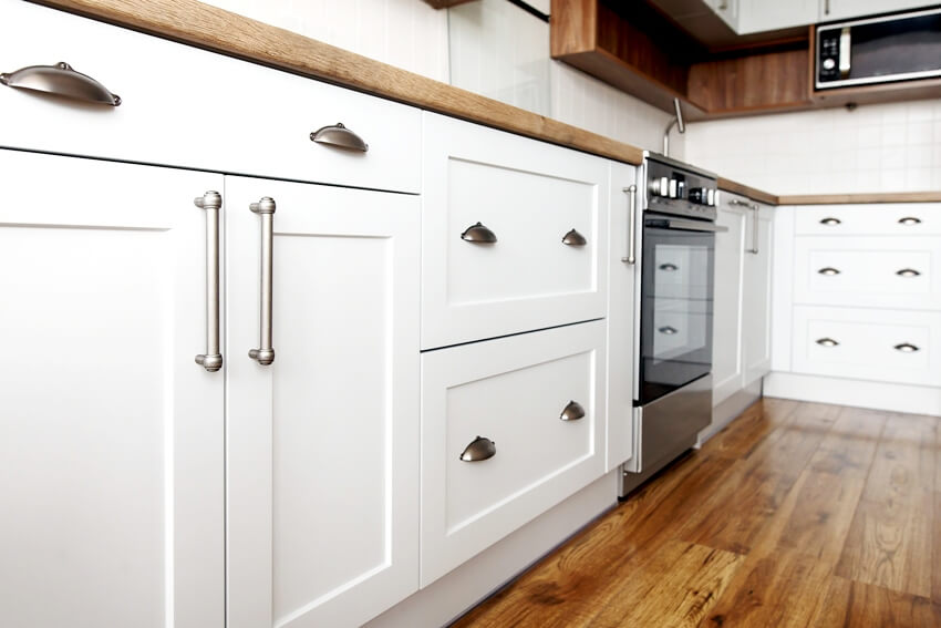 Stylish aluminum handles on inset shaker cabinet doors in Scandinavian style kitchen