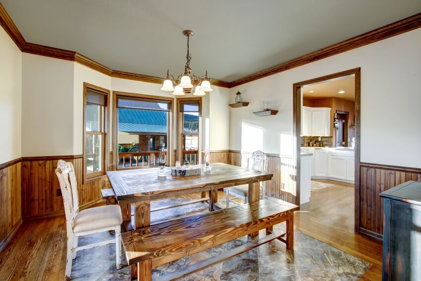 Traditional dining room with old wood furniture and accessories accented with half wood paneling on the walls and hardwood floor decorated with natural stone tiles