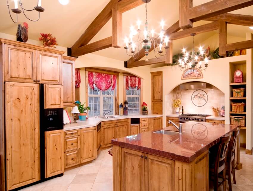 Traditional kitchen features pine cabinetry, wood beams, granite counters, and antique looking chandeliers
