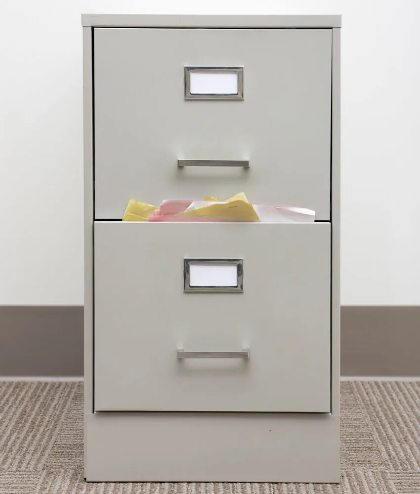 A vertical file cabinet stuffed with papers